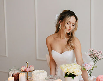  white girl in a wedding dress with differnt  candle on the table around the cake that are Eco friendly 