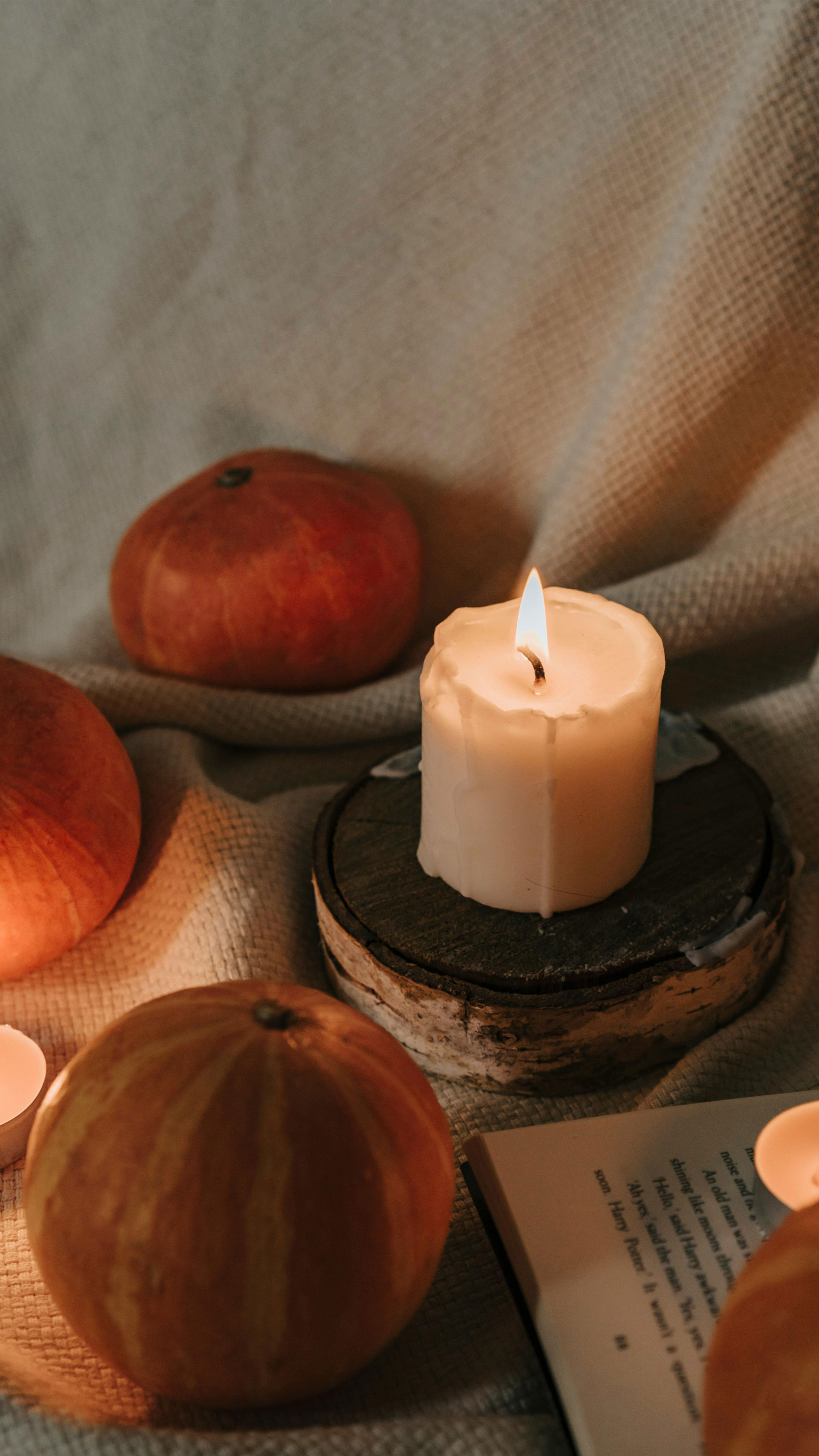  small candle that have been litten with a pumkin in the background for the seasonal season sheniqua scented candles is always ready
