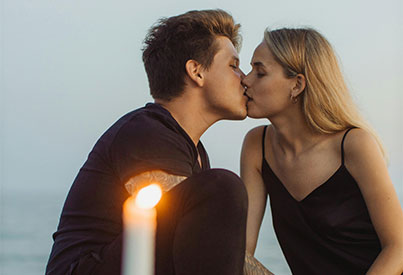  image shows a cuple kissing with a white candle